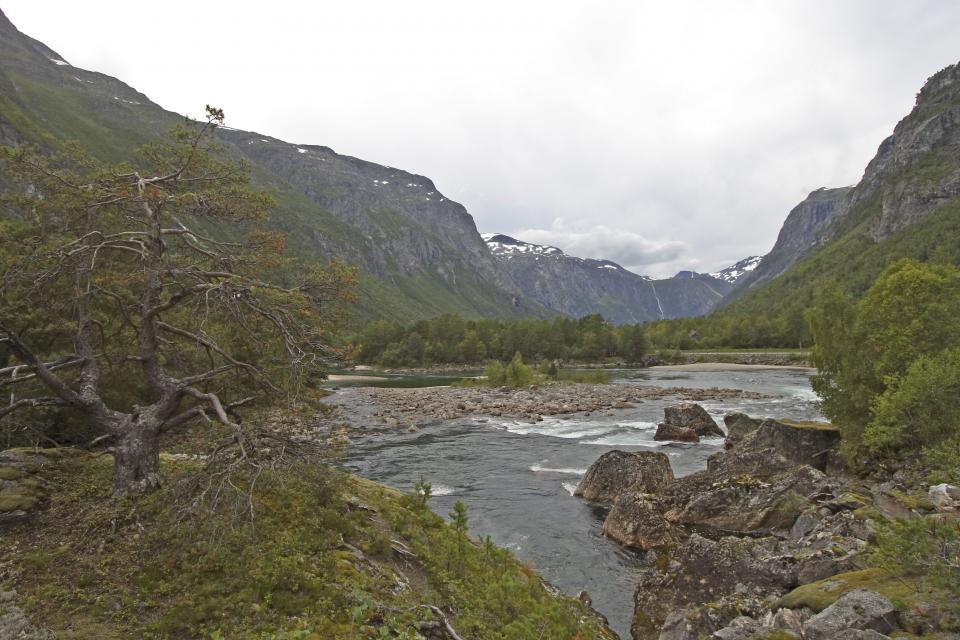 Rauma renner i et idyllisk landskap, med den dramatiske Trollveggen på den ene sida.