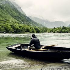 Laksefisker i båt ved elvebredden.